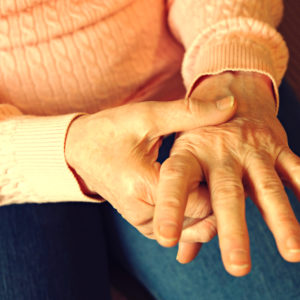 Senior woman grasps painful hand caused by arthritis