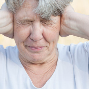 senior woman covering ears