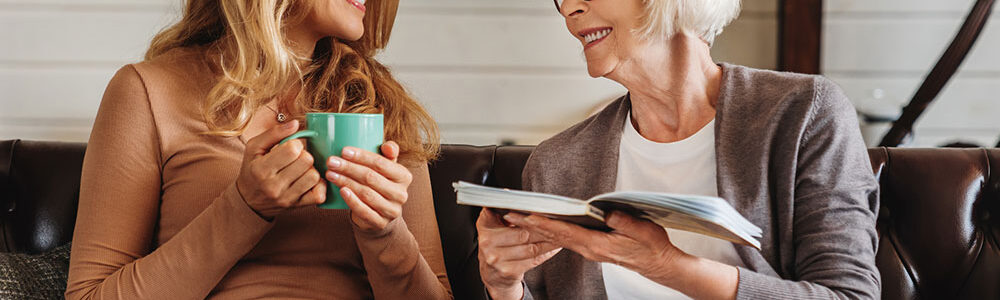 Two women sitting next two each other talking