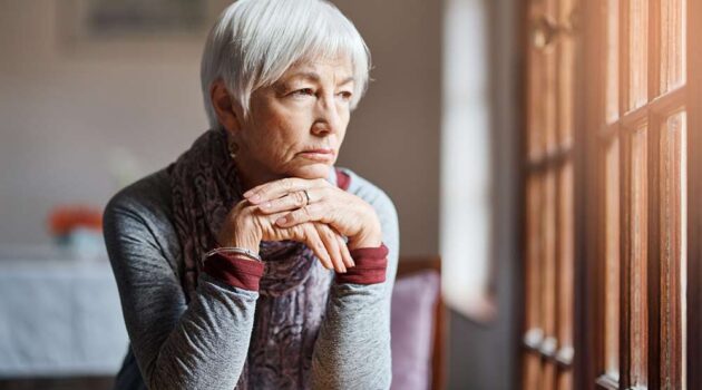 Lady sitting holding head in hand staring off in the distance contemplating her existence.