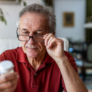 Older man reading medicine label.
