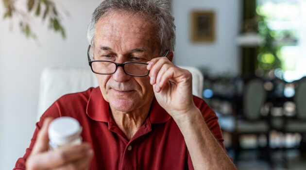 Older man reading medicine label.
