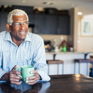 Man smiling and sitting in kitchen.