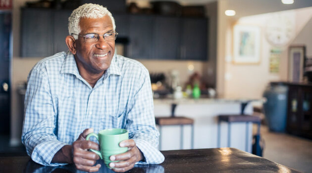 Man smiling and sitting in kitchen.