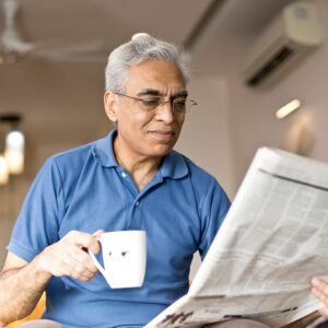 Man drinking a drink and reading the newspaper.