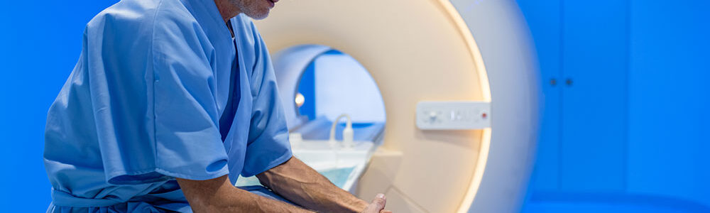 Man sitting on bench of MRI machine.