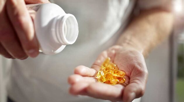 Person pouring pills out of bottle into hand.
