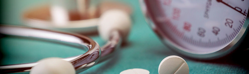 Doctor's stethoscope on a table next to pills.