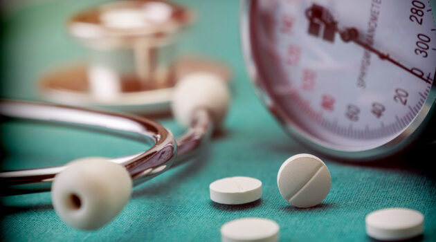 Doctor's stethoscope on a table next to pills.