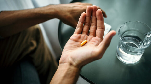 Person loooking at pill in hand.