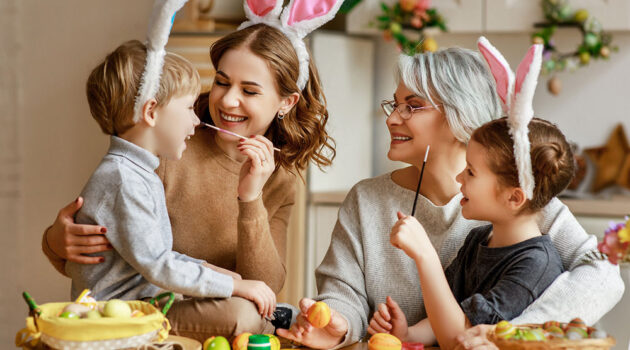 family mother, grandmother and children paint eggs for holiday