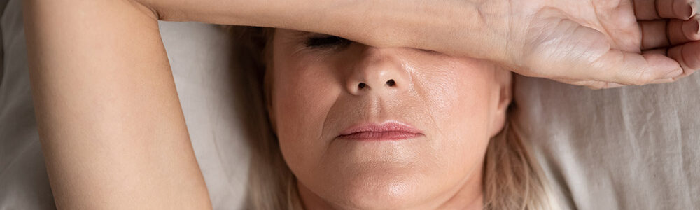 Woman covering eyes in bed