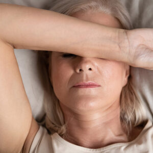 Woman covering eyes in bed