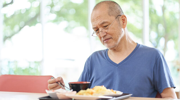 Man sitting in front of food at a table.