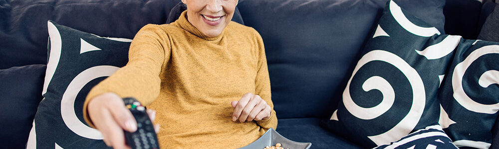 Senior lady sits on couch snacking on microbiome friendly snack