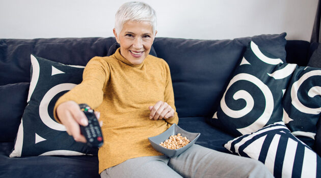 Senior lady sits on couch snacking on microbiome friendly snack