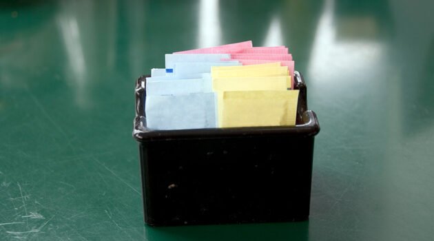 Artificial sweetener packets in black container includes yellow sucralose package